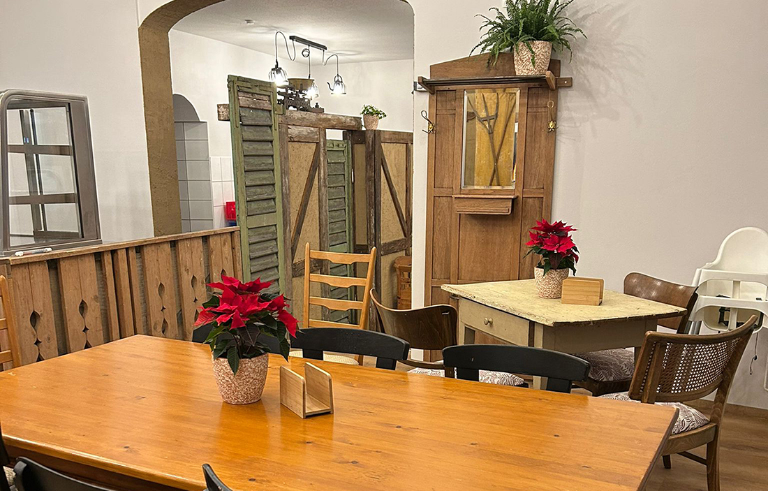 Gemütlicher Gastraum mit Holztischen, verschiedenen Stühlen und weihnachtlicher Dekoration, darunter rote Weihnachtssterne und Zimmerpflanzen im Staufen Suppentöpfle in der Göppinger Innenstadt.
