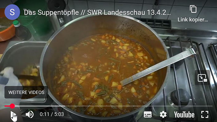 Großer Edelstahltopf mit frisch gekochter Gemüsesuppe in einer Industrieküche, aufgenommen während des SWR-Landesschau-Beitrags ‚Das Suppentöpfle‘. Sichtbar sind Kartoffelstücke, grüne Bohnen, Karotten und eine kräftige Brühe, daneben ein Kochutensil auf dem Herd.